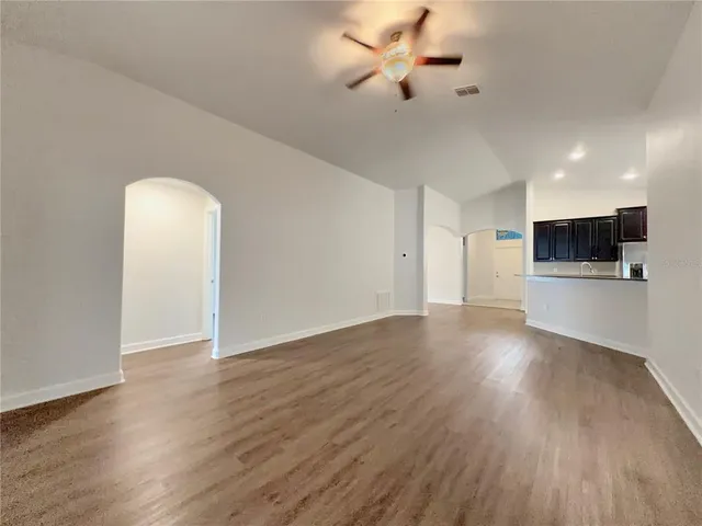 a view of an empty room with a kitchen and wooden floor