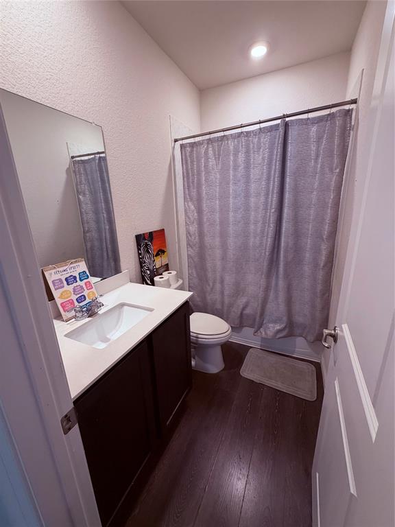 2001 Juniper Pass Way Mesquite, TX 75149 - Photo 11 of 12 Full bathroom with vanity, dark wood-style flooring, shower / tub combo with curtain, and a textured wall
