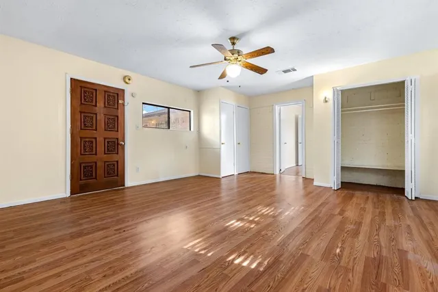 a view of empty room with wooden floor and fan