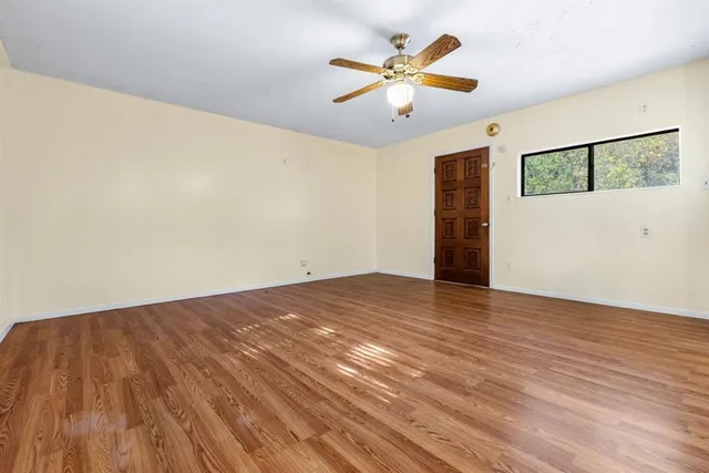 an empty room with wooden floor and windows
