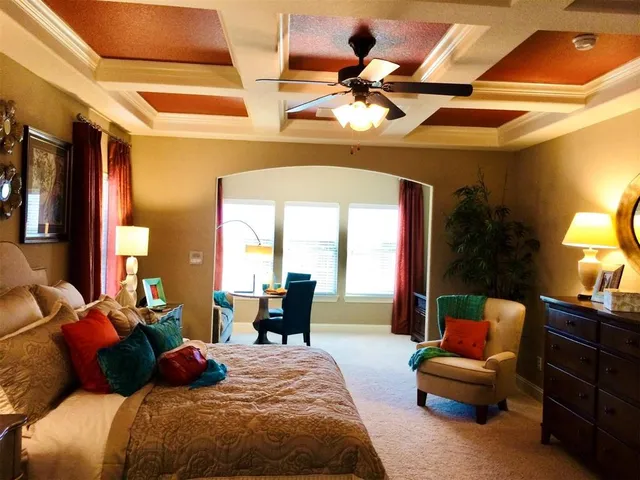 a bedroom with a bed a couch and dresser with wooden floor