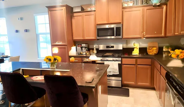 a kitchen with stainless steel appliances granite countertop a sink a stove a microwave a refrigerator and cabinets