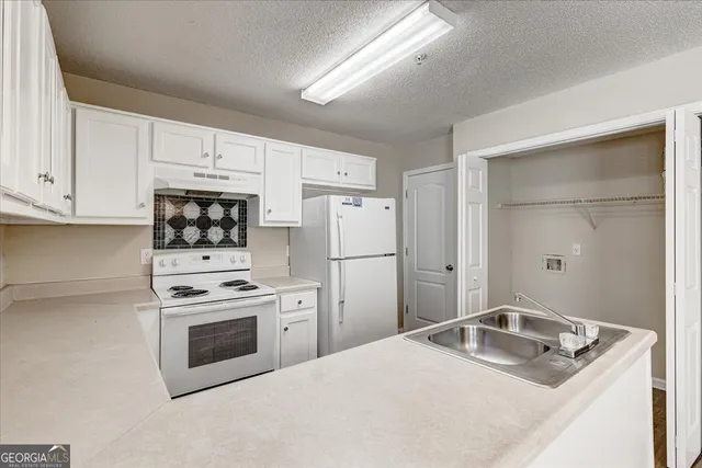 a kitchen with white cabinets and white appliances
