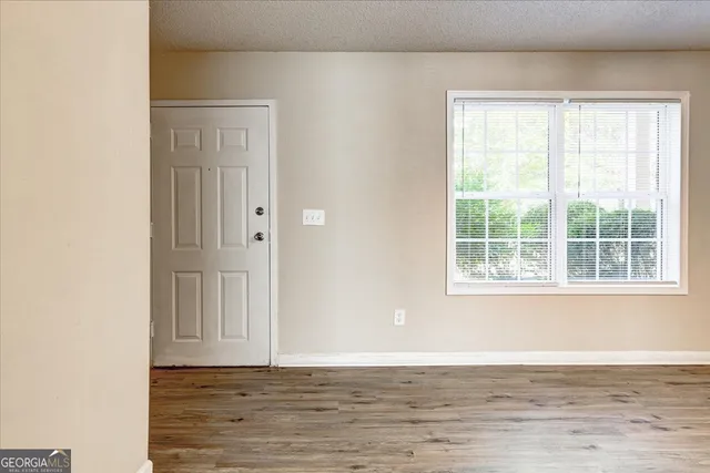 a view of an empty room with wooden floor and a window
