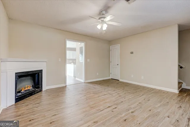 a view of an empty room with wooden floor fireplace and a window
