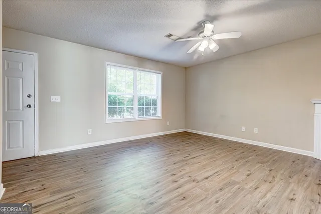 a view of an empty room with wooden floor and a window