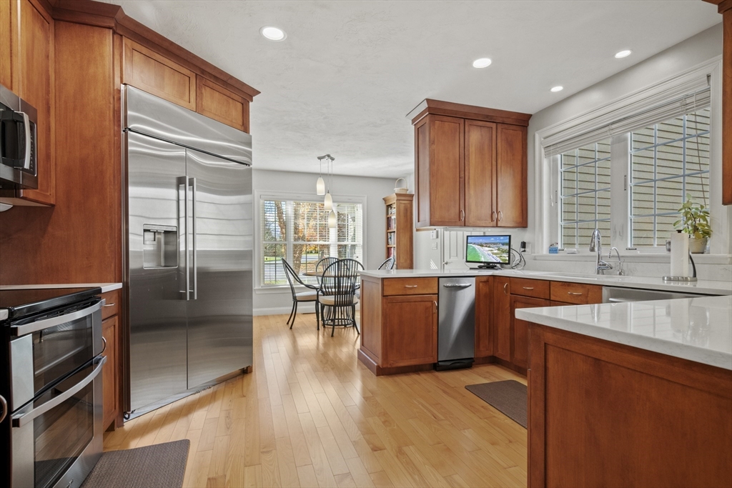 36 Caldwell Farm Road, Unit 36 Newbury, MA 01922 - Photo 10 of 42 a kitchen with stainless steel appliances granite countertop a stove top oven a sink dishwasher a dining table and chairs with wooden floor
