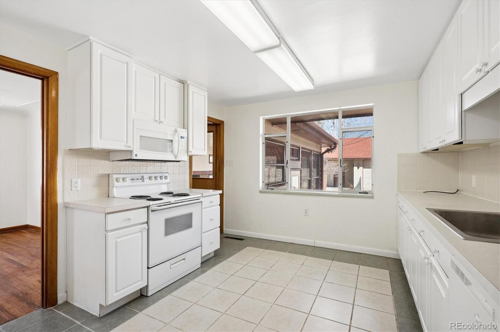 7505 West 47th Avenue Wheat Ridge, CO 80033 - Photo 17 of 35 a kitchen with white cabinets and white appliances
