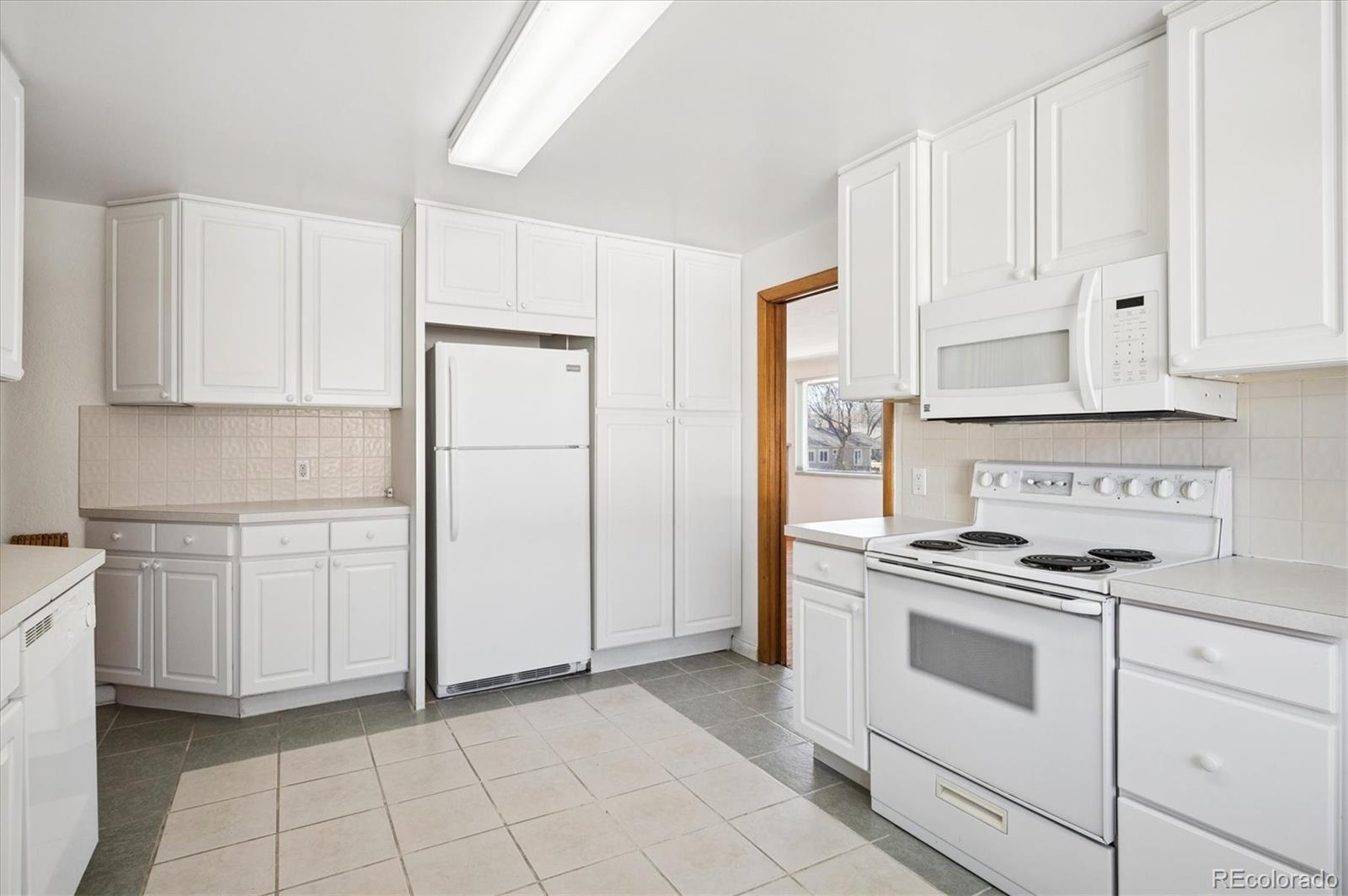 7505 West 47th Avenue Wheat Ridge, CO 80033 - Photo 18 of 35 a kitchen with white cabinets and white appliances