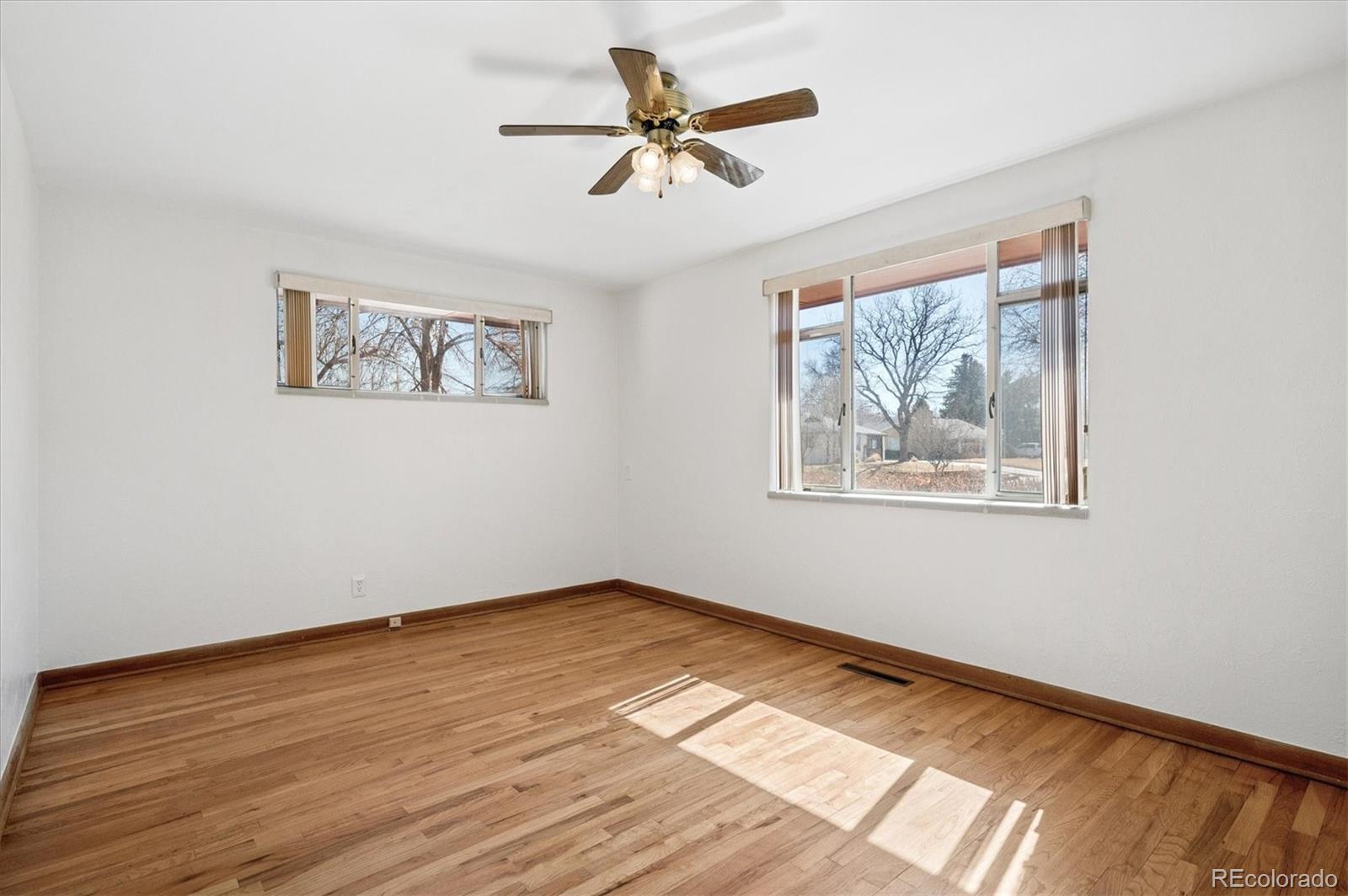 7505 West 47th Avenue Wheat Ridge, CO 80033 - Photo 19 of 35 a view of an empty room with wooden floor and a ceiling fan