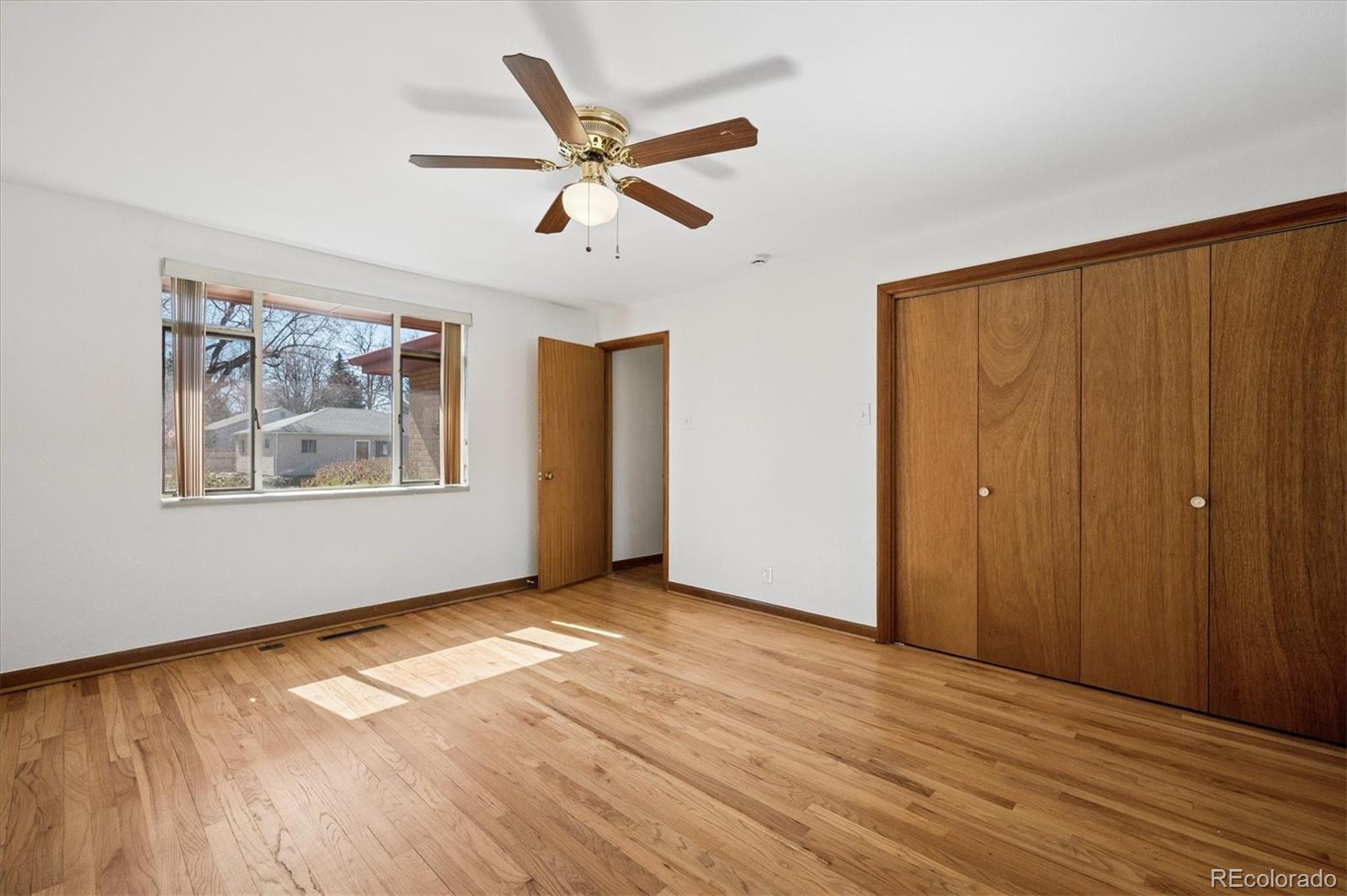 7505 West 47th Avenue Wheat Ridge, CO 80033 - Photo 23 of 35 an empty room with wooden floor chandelier fan and windows