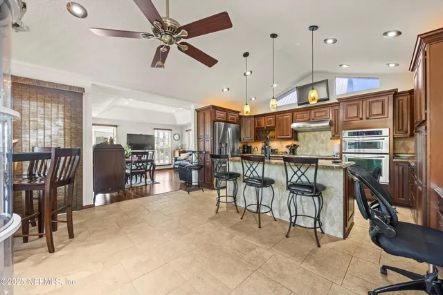 a kitchen with stainless steel appliances granite countertop a stove top oven a sink a dining table and chairs