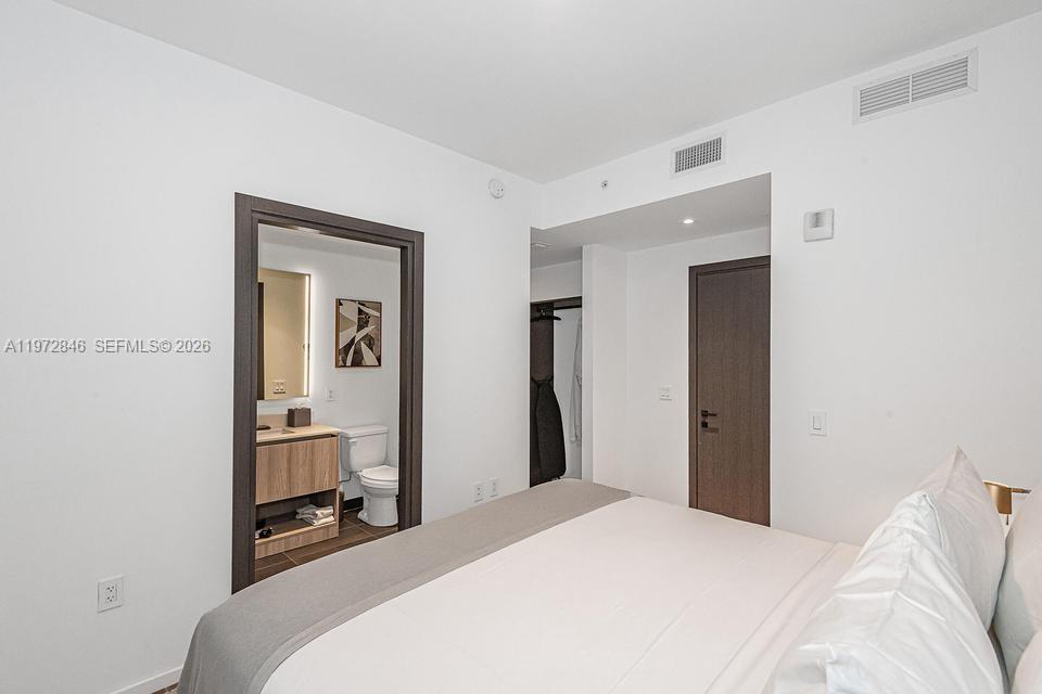 398 Northeast 5th Street, Unit 2418 Miami, FL 33132 - Photo 24 of 34 a bedroom with a bed and a mirror