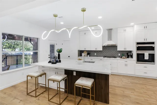 a kitchen with stainless steel appliances kitchen island granite countertop a sink a stove and a wooden floors