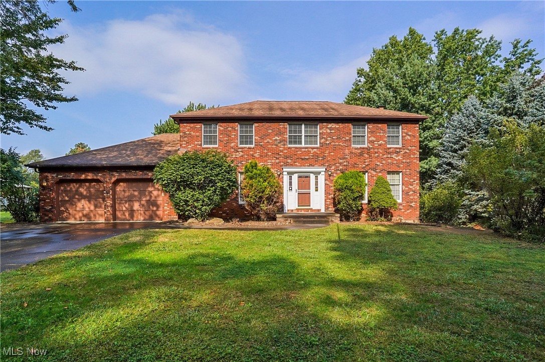 7300 Morley Road Painesville, OH 44077 - Photo 1 of 50 Colonial house with brick siding, a front yard, asphalt driveway, and an attached garage