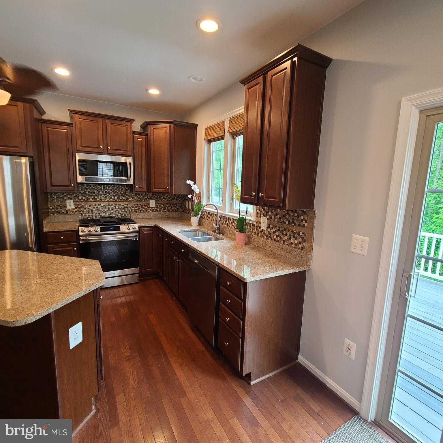a kitchen with stainless steel appliances granite countertop wooden cabinets a sink a stove a refrigerator and island