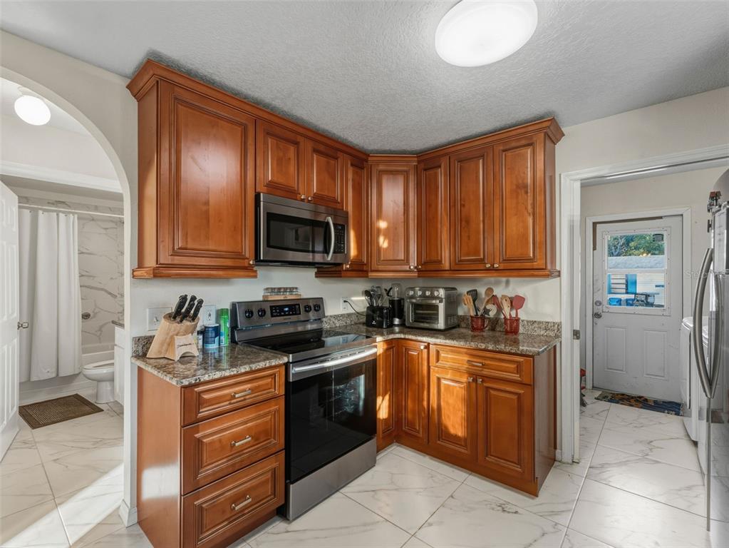5104 Timberlan Street Tampa, FL 33624 - Photo 12 of 27 a kitchen with stainless steel appliances granite countertop wooden cabinets a stove top oven a sink and dishwasher