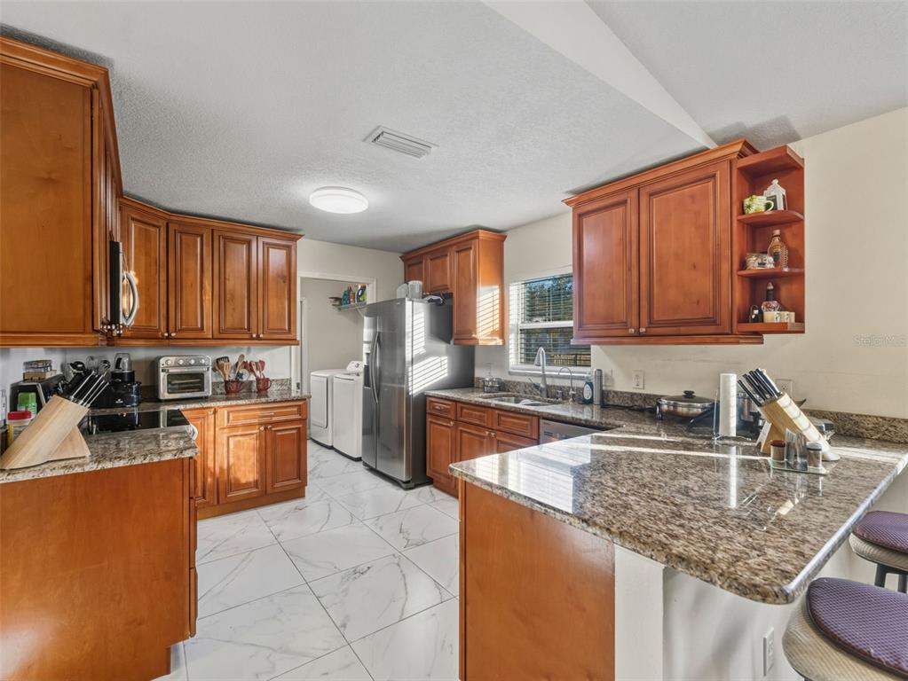 5104 Timberlan Street Tampa, FL 33624 - Photo 10 of 27 a kitchen with stainless steel appliances granite countertop a sink stove and cabinets