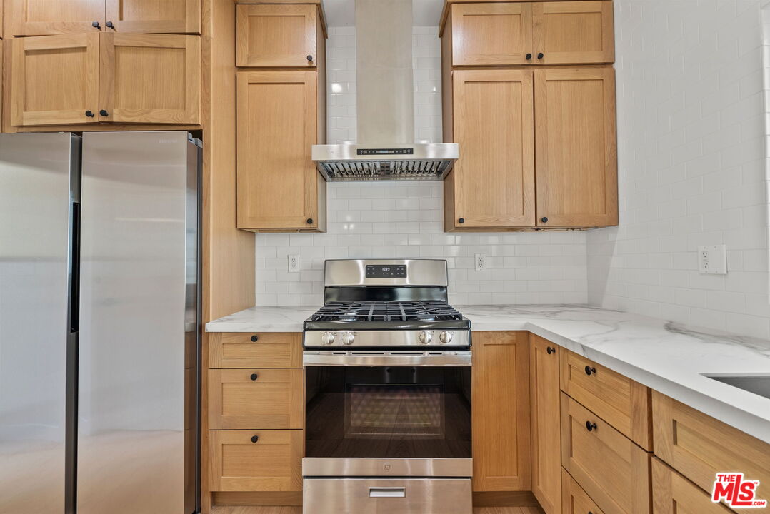128 South Swall Drive, Unit 1/2 Los Angeles, CA 90048 - Photo 8 of 32 a kitchen with stainless steel appliances granite countertop a stove and a refrigerator