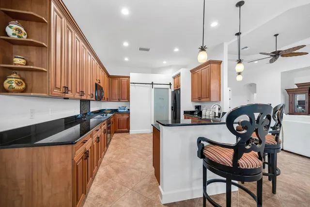 a kitchen with granite countertop a table chairs a sink dishwasher refrigerator and cabinets