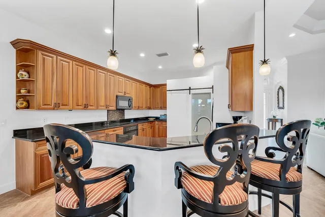 a kitchen with granite countertop a sink a stove a dining table chairs and mirrors