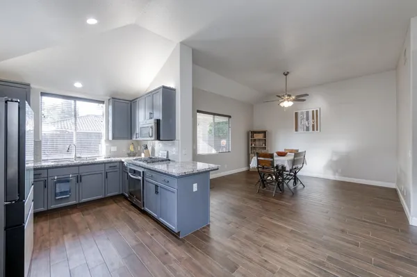 an open kitchen with granite countertop a sink dining table and chairs