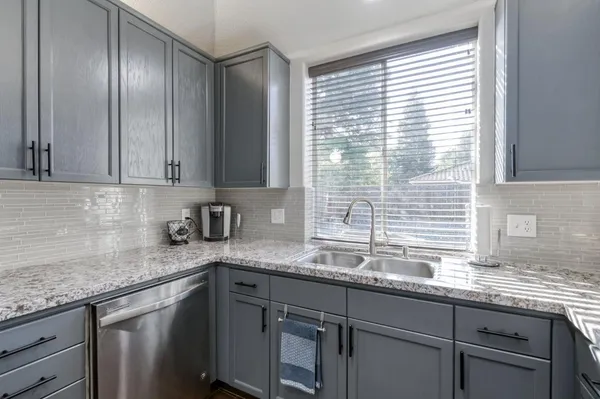 a kitchen with granite countertop stainless steel appliances a sink window and cabinets