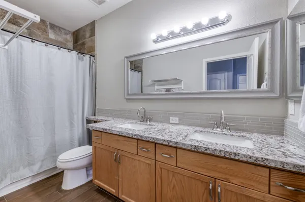 a bathroom with a granite countertop sink a toilet and a mirror