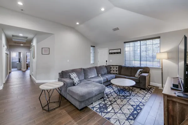 a living room with furniture a large window and wooden floor