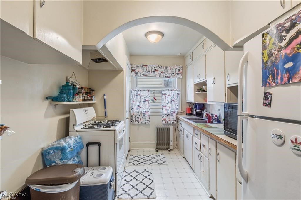 642 East Wilbeth Road Akron, OH 44306 - Photo 10 of 39 Unit 1 Kitchen with white appliances, white cabinetry, radiator, and light tile patterned floors