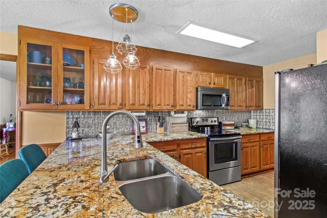 a kitchen with granite countertop a stove a sink and a microwave
