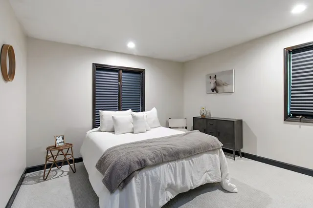 a bedroom with a bed a painting on the wall and a window