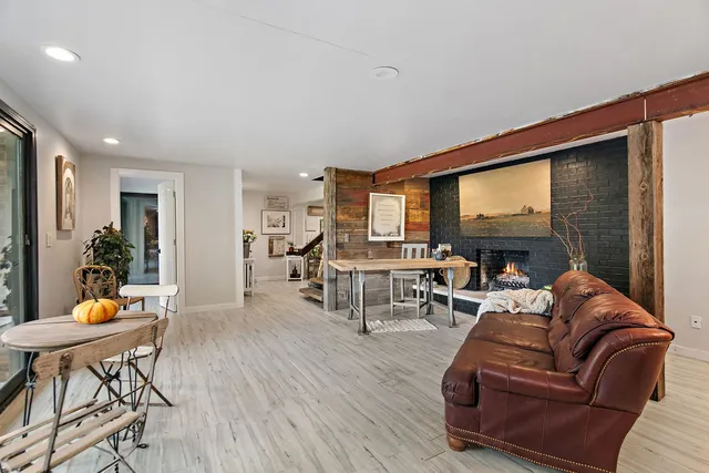 a living room with furniture a fireplace and a dining table with kitchen view