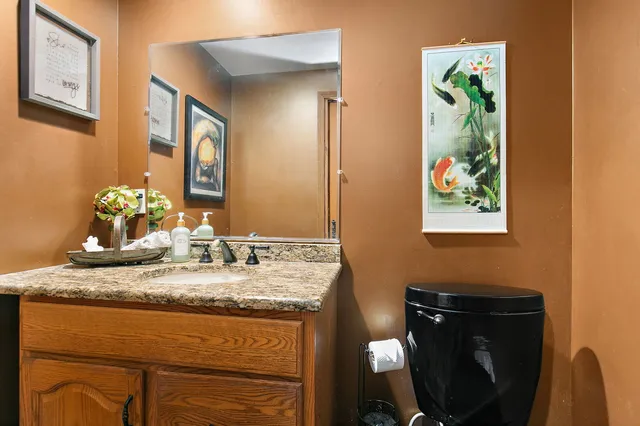 a bathroom with a granite countertop sink a mirror and painting on the wall