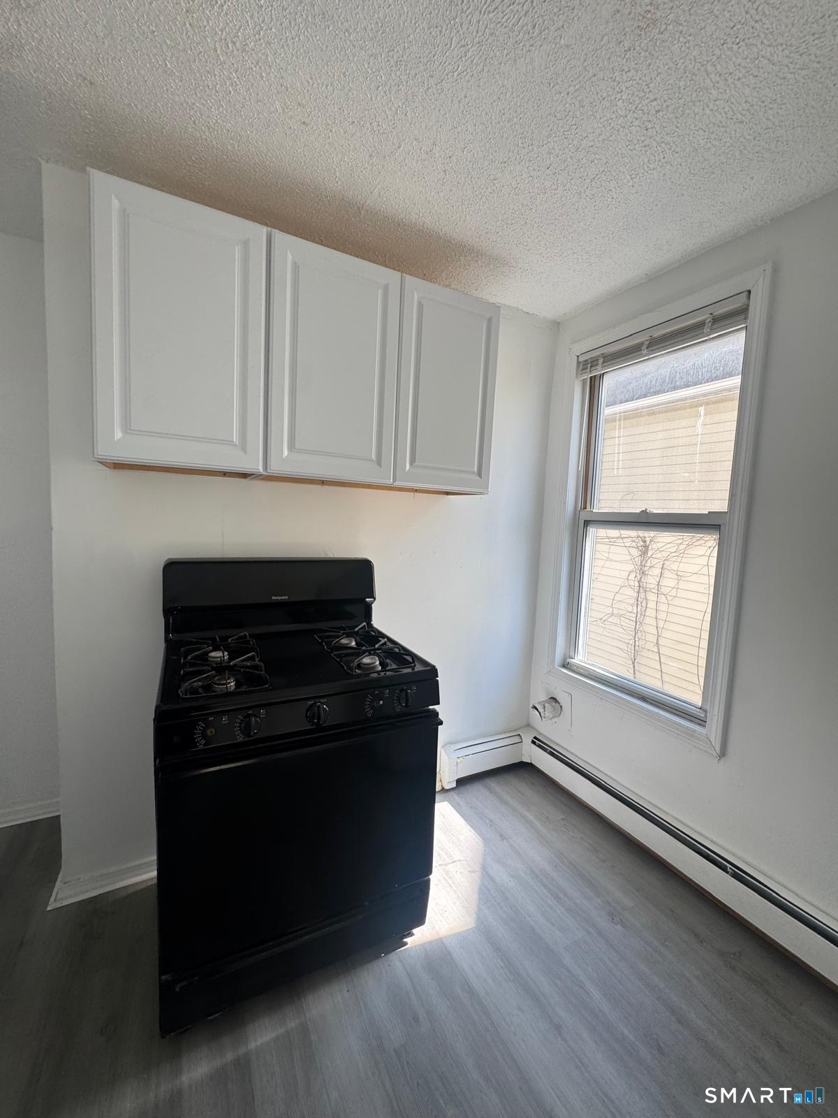 265 6th Street Bridgeport, CT 06607 - Photo 2 of 9 a kitchen with wooden floors and a stove