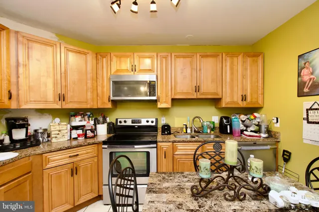 a kitchen with stainless steel appliances a stove a sink a refrigerator cabinets and a window