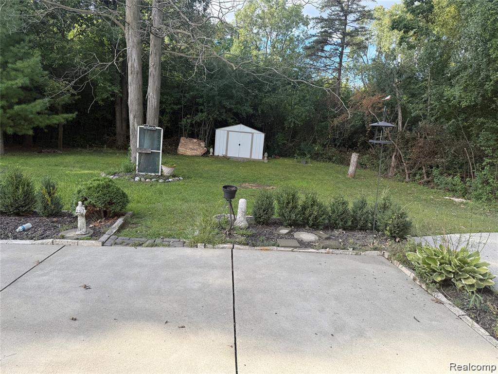 43038 Hanford Road Canton, MI 48187 - Photo 5 of 36 Expansive concrete patio transitioning to a lush green lawn, bordered by decorative plantings and mature trees