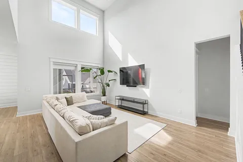 a living room with furniture a flat screen tv and large windows