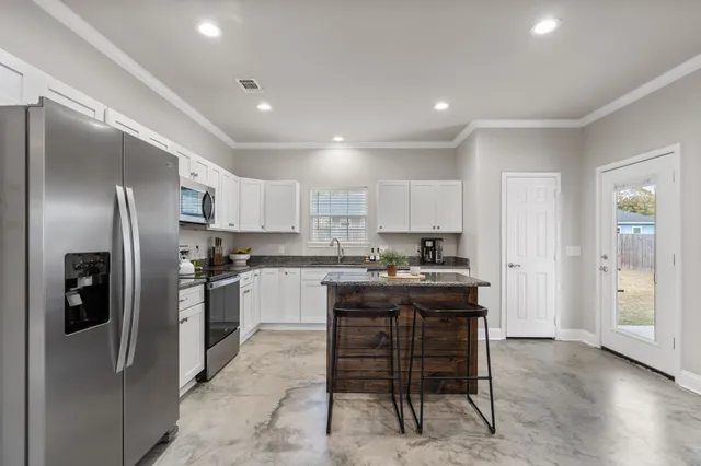 a kitchen with kitchen island a refrigerator stove microwave and cabinets
