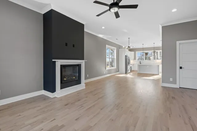a view of a livingroom with a fireplace a ceiling fan and wooden floor