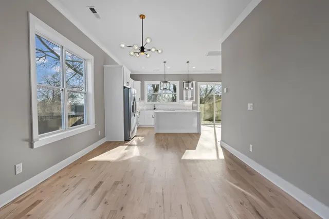 a view of an empty room with a window and wooden floor