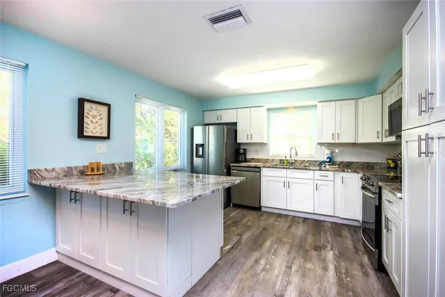 a kitchen with a stove a sink a refrigerator and white cabinets with wooden floor