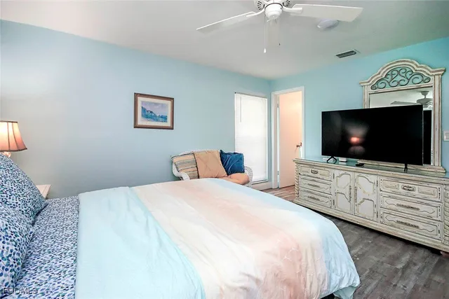 a bedroom with a flat screen tv on dresser and a chandelier