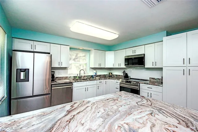 a kitchen with granite countertop a refrigerator stove top oven and sink