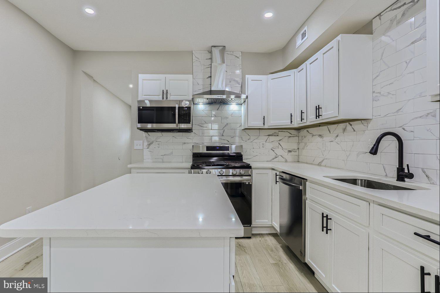 2829 Miles Avenue Baltimore, MD 21211 - Photo 12 of 25 a kitchen with stainless steel appliances a stove sink and cabinets