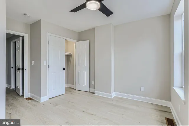 an empty room with closet and a chandelier fan