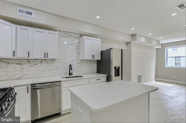 a kitchen with stainless steel appliances a sink a stove a refrigerator and cabinets