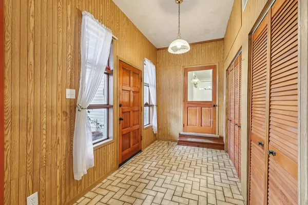 an empty room with wooden floor closet and windows