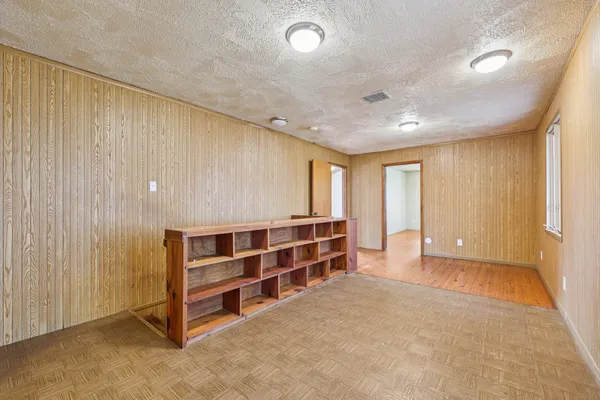a view of empty room with wooden floor and fan