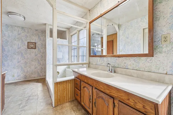 a bathroom with a tub sink and mirror
